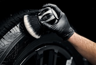a man with a glove on his hand is polishing the tire of a car